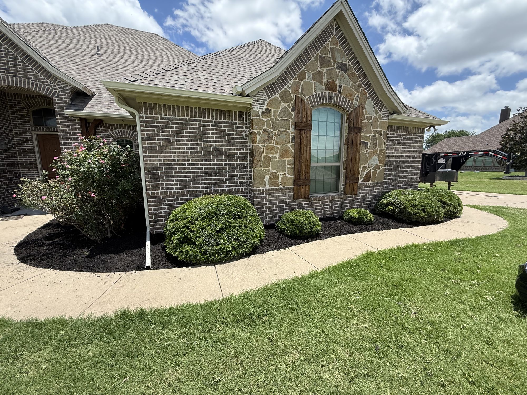 Stone-and-brick home with edged, mulched beds and a green lawn